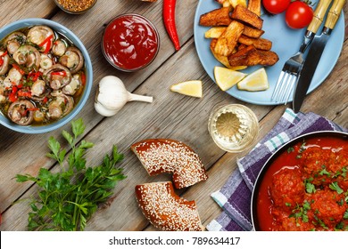 Dining table with meatballs in tomato and marinated mushrooms. Wine and various snacks. - Shutterstock ID 789634417