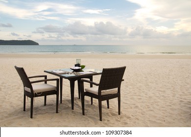 Dining Table Prepared For Two On White Sand Beach Close To Ocean