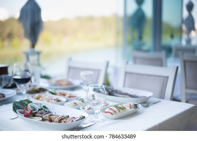 Dining Table At River And Trees With Seafood Dishes. Outside Dining Or Lunch Concept. Dining And Eating In The Beautiful Nature At Open Air Restaurant. Lunch In Nature