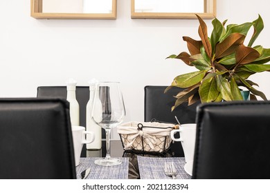 Dining Table With Service For Two And Black Leather Armchairs And Beautiful Decorative Plant In A Vacation Rental Apartment