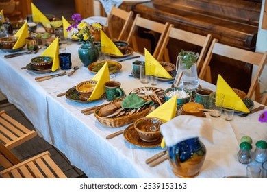 A dining table set with ceramic dishes, yellow napkins, and a floral centerpiece. Wooden chairs surround the table, with a piano in the background. - Powered by Shutterstock