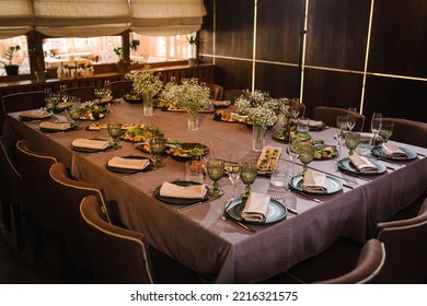 Dining Table Set Up With Glasses And Tableware For An Evening Dinner Party. Banquet Hall Decorated Served Table. Birthday Party, Bachelorette Party, Wedding. Setting Festive Table Decor With Flowers.