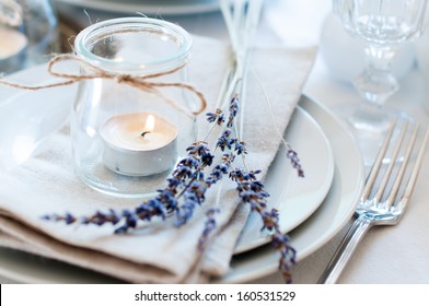 Dining table setting at Provence style, with candles, lavender, vintage crockery and cutlery, closeup. - Shutterstock ID 160531529