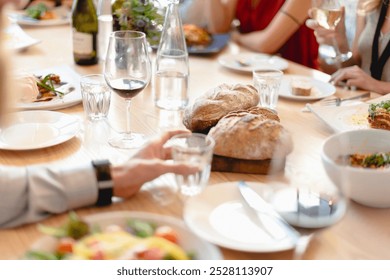 A dining table with wine glasses, bread, and various dishes. People enjoying a meal, sharing food, and socializing. Lunch and dining with friends. People at a fancy business lunch at restaurant.