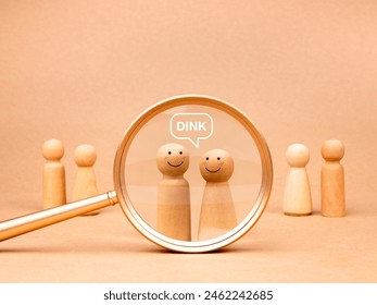 DINK concept, Double income, no kids or dual income, no kids, referring to couples who are voluntarily childless. Acronym text with wooden figures, happy male and female in magnifying glass lens.