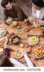 Dinner With Best Friends. Top View Of Four People Having Dinner Together While Sitting At The Rustic Wooden Table