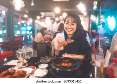 Dinner Couple Date At Indoor Restaurant Concept. Portrait Happy Smile Young Adult Asian Woman Holding Fried Chicken At Korean Meal. Foodie People Lifestyle.