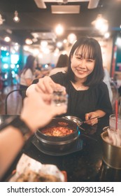 Dinner Couple Date At Indoor Restaurant Concept. Portrait Happy Smile Young Adult Asian Woman Cheer With Soju At Korean Chicken Meal. Foodie People Lifestyle.