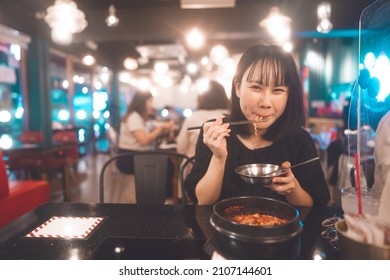 Dinner couple date at indoor restaurant concept. Portrait happy smile young adult asian woman eating noodle at Korean meal. Foodie people lifestyle.