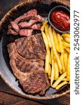 Dinner with grilled Chuck eye roll steak and french fry on a plate. wooden background. top view