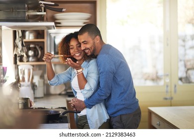 Dinner made with love. Shot of a young woman giving her husband a taste of the food that shes preparing at home. - Powered by Shutterstock