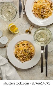 Dinner With Pasta Linguine With Swordfish, Butter, Lemon Sauce, Decorated With Caper Flowers. White Wine. Table Setting. Top View, Vertical Image.