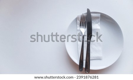 Dinner place setting. White empty plate , silver fork and knife on white background, top view, copy space