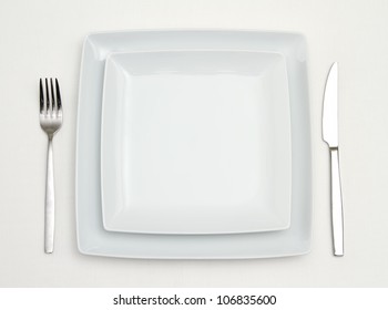 Dinner Place Setting. White Square China Plates With Silver Fork And Knife