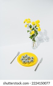 Dinner Set With Yellow Flowers In Jug, Plastic Plate With Disco Balls And Cutlery On White Background. Minimal Concept.