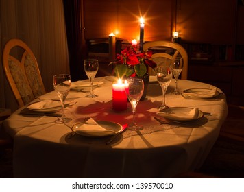 Dinner table at candlelight with flowers, glasses and plates