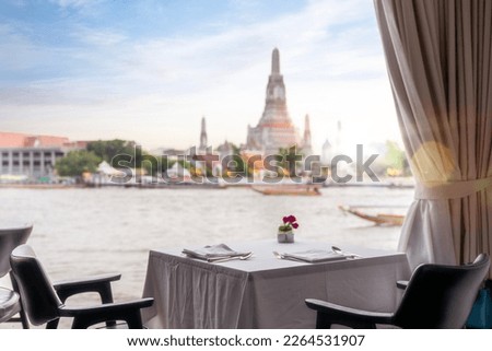 Dinner table in restaurant with Wat arun pagoda and temple back ground in Bangkok city, Thailand