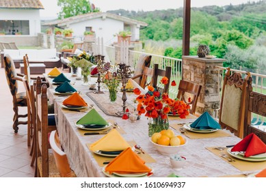 Dinner Table Set In Italy, In Tuscany. Bright Modern Dinner Table Decor With Wildflowers Bouquets, Poppies And Candles