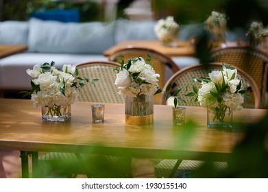 Dinner table setting with dishes, vases with with flowers and candles