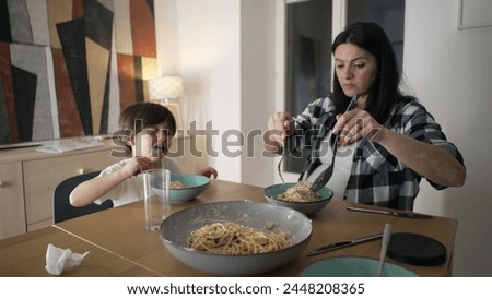Dinner Together - Mother Serving Spaghetti Pasta on plate while son eats food, Nurturing Mealtime Bond at home