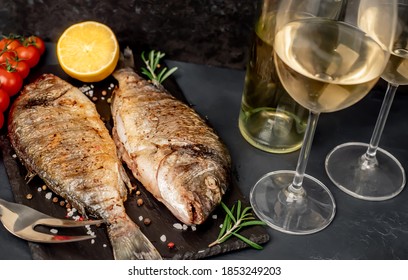 Dinner For Two. Grilled Dorado Fish With Spices And A Bottle Of White Wine With Glasses On A Stone Background