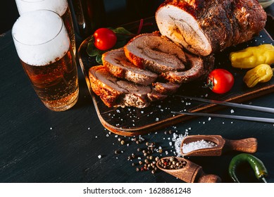 dinner for two of meat and craft beer. two glasses of beer, baked chopped meat with vegetables on a wooden tray with a meat fork and spices