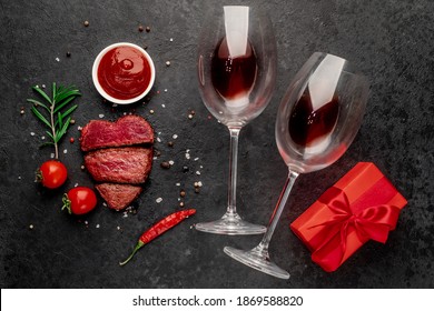 Dinner For Two. Three Pieces Of Meat. Three Types Of Roast Meat, Rare, Medium, Well Done In The Shape Of A Heart, Two Glasses Of Red Wine And A Gift On A Stone Background