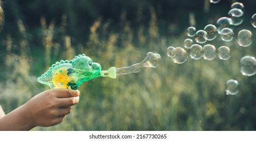 Dinosaur Soap Bubble Gun Shooter, Blower. Party For Kids. Girls,chidren Playing Funny Family Game With Dad, Father. Outdoors Activity In Summer In Green Park. Big Flying Bubbles.