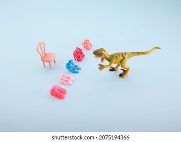 Dinosaur Toy And Doll's Shoes, Minimal Funny Composition Against Pastel Blue Background. Summer Shoe Sale Theme. Mad Customer Idea.