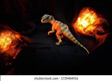 Dinosaur Toy Isolated A Black Background With Burning Red Fire Spark,  Create Horror Mood With Toy Dinosaur