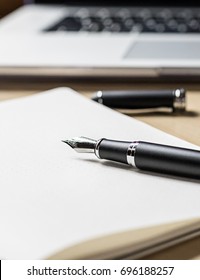 Dip Pen On Notebook On Wooden Table