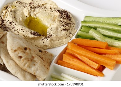 A Dip Tray With Hummus, Bread, Carrot Sticks, Celery And Cucumber.