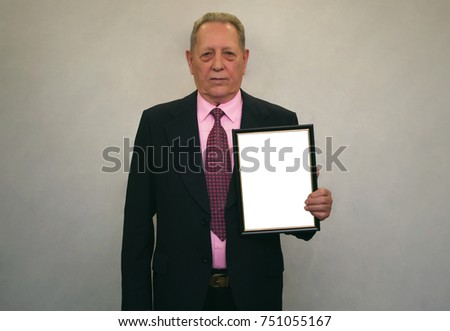 Diploma. Best employee certificate. Grateful letter. Accolade. Thanks letter. Elderly senior man in black suit and tie holding in hands empty blank photo frame. Appreciation document.