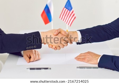 Diplomatic meeting between Russia and United States. Political representatives of American and Russian states shake hands before negotiations begin. Close up of handshake of male diplomats.