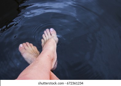 Dipping Feet In Water Off A Dock On A Hot Summer Day.