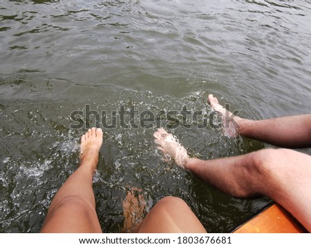 Dipping feet in water off a dock on a hot summer day.Female and male feet on summer beach against the sea, toned. Family traveling concept