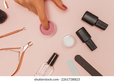 Dipping powder manicure tools on pink background. Woman dip her finger nail in the colorful powder
