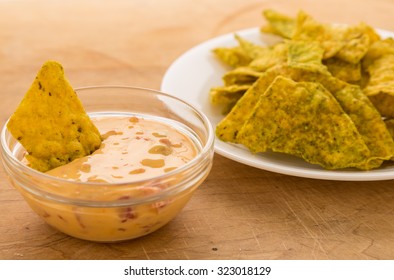 Dipping Spicy Jalapeno Tortilla Chips In Creamy Chili Con Queso Dip In Clear Glass Bowl.
