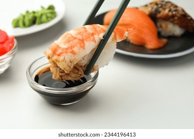 Dipping tasty sushi into soy sauce at white table, closeup. Space for text - Powered by Shutterstock