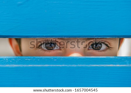 direct look of a child between the blue wooden planks