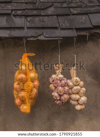Direct marketing of garlic braid and onions hanging in front of old facade