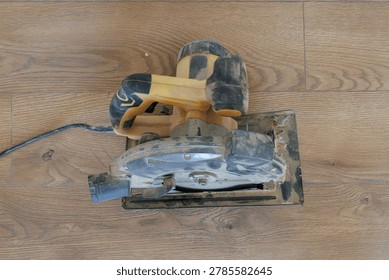 Direct overhead flat lay view of a used circular saw on a dark brown wooden floor.