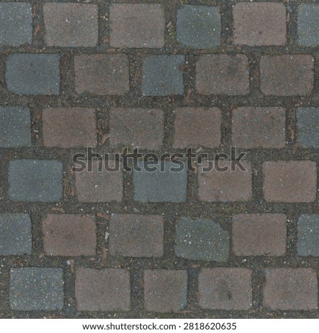 Direct overhead view of weathered multi-colored square stone cobblestones set in dark soil and gravel.