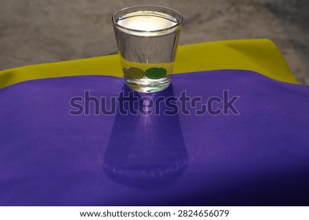 Direct Sunlight Caustic Shadow. A water glass with marbles casts a sharp caustic light refection pattern on colorful paper under bright outdoor sunlight.