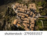 A direct top-down drone view highlighting the geometric pattern of terracotta tiled roofs, stone alleys, and a central courtyard in a medieval hilltop town.