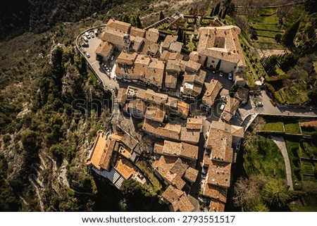 A direct top-down drone view highlighting the geometric pattern of terracotta tiled roofs, stone alleys, and a central courtyard in a medieval hilltop town.