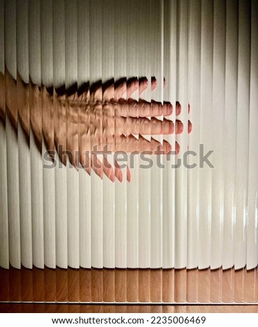 Direct view of a hand with back light through fluted glass on white background. Distorted image of hand by vertical stripes corrugated glass. Abstract illusion. 