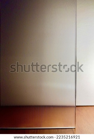 Direct view through corrugated glass. Clear fluted glass with back light against white paper background. 