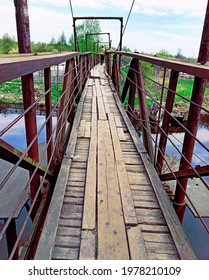 A Direct Way Forward Along An Old Narrow Bridge With A Rusty Metal Frame And Uneven Flooring Made Of Boards.