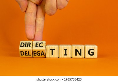 Directing or delegating leadership style symbol. Businessman turns cubes, changes words 'delegating' to 'directing'. Beautiful orange background, copy space. Business, directing or delegating concept.